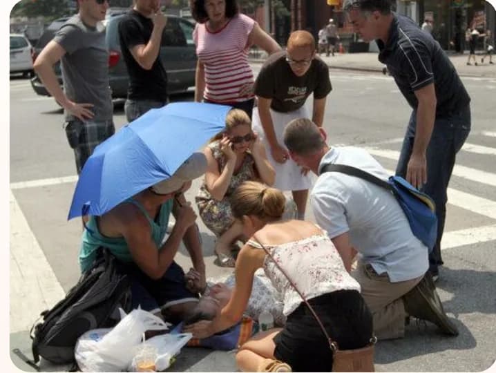 Bystanders helping someone suffering in the heat on a city street