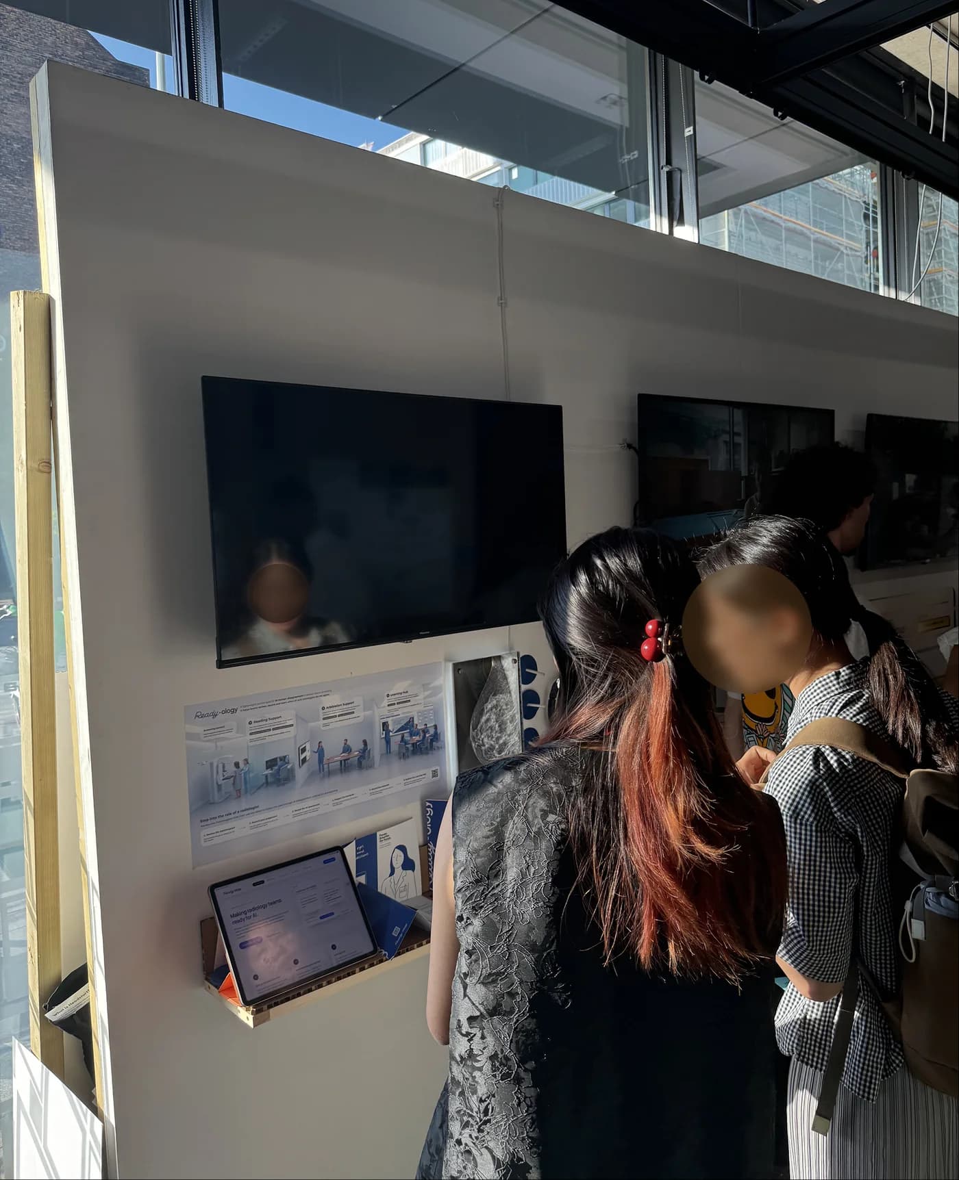 Visitors reviewing the Human–AI disagreement content on the exhibition display screen, faces anonymised
